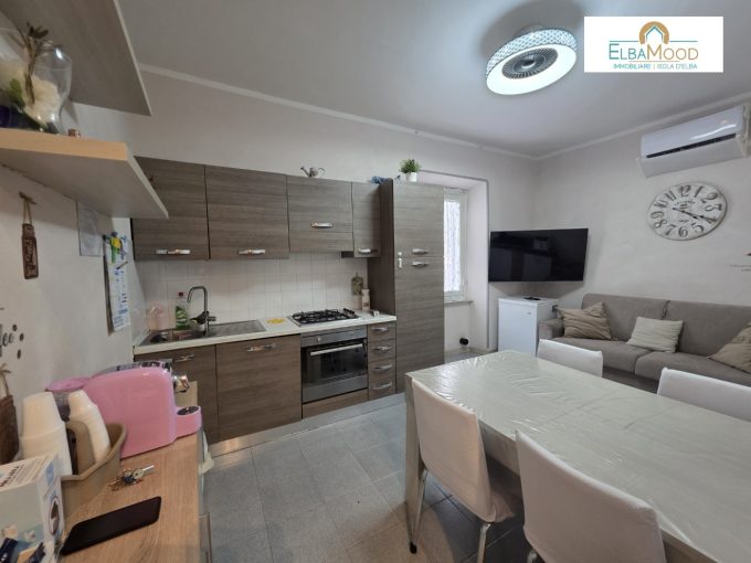 Accogliente Trilocale nel Cuore di Porto Azzurro: Comodità e Indipendenza a Due Passi dal MareNel cuore pulsante del suggestivo borgo marinaro di Porto Azzurro, questa proprietà rappresenta la sintesi perfetta tra comfort domestico e vita di mare, posizionata strategicamente in una zona pianeggiante e vicina a ogni servizio.Il Tour degli Interni: Ambienti Funzionali e Ben OrganizzatiLa Zona Giorno: Oltre la soglia d'ingresso si viene accolti da un ampio e luminoso ambiente che unisce il soggiorno e la zona cottura. Questa configurazione a pianta aperta crea un’atmosfera conviviale e moderna, ideale per i momenti di relax in famiglia o per cenare in compagnia dopo una giornata in spiaggia.La Zona Notte: Un disimpegno razionale conduce alle due camere da letto. Gli spazi interni sono studiati per garantire massima privacy e comfort, offrendo la flessibilità necessaria per ospitare una famiglia numerosa o per accogliere gli amici durante la stagione estiva.I Servizi: Il bagno, funzionale e ben disposto, è affiancato da un locale lavanderia separato. Questo vano accessorio rappresenta un valore aggiunto introvabile, fondamentale per mantenere l'ordine e gestire al meglio le necessità quotidiane o i flussi dei soggiorni turistici.I Punti di Forza: Zero Spese e Rendita GarantitaL'immobile è inserito all'interno di una piccola ed intima realtà residenziale, completamente priva di spese condominiali. Questa caratteristica assicura una gestione economica e lineare nel tempo. Si rivela una scelta vincente per diverse finalità: una solida prima casa, un rifugio sicuro per le vacanze o un investimento immobiliare ad alta redditività, pronto per essere inserito nel circuito degli affitti brevi.La Posizione: Il Vero Valore AggiuntoLa location è il fiore all'occhiello di questa proposta. Trovarsi nel centro pianeggiante di Porto Azzurro significa sposare uno stile di vita rilassato, dove l'auto non è più una necessità. Le caratteristiche piazze del borgo, le botteghe artigiane, i ristoranti sul porto e le incantevoli spiagge paesane si raggiungono con una piacevole passeggiata di pochi minuti. Una combinazione di spazio, centralità e indipendenza davvero rara da trovare sul mercato locale.